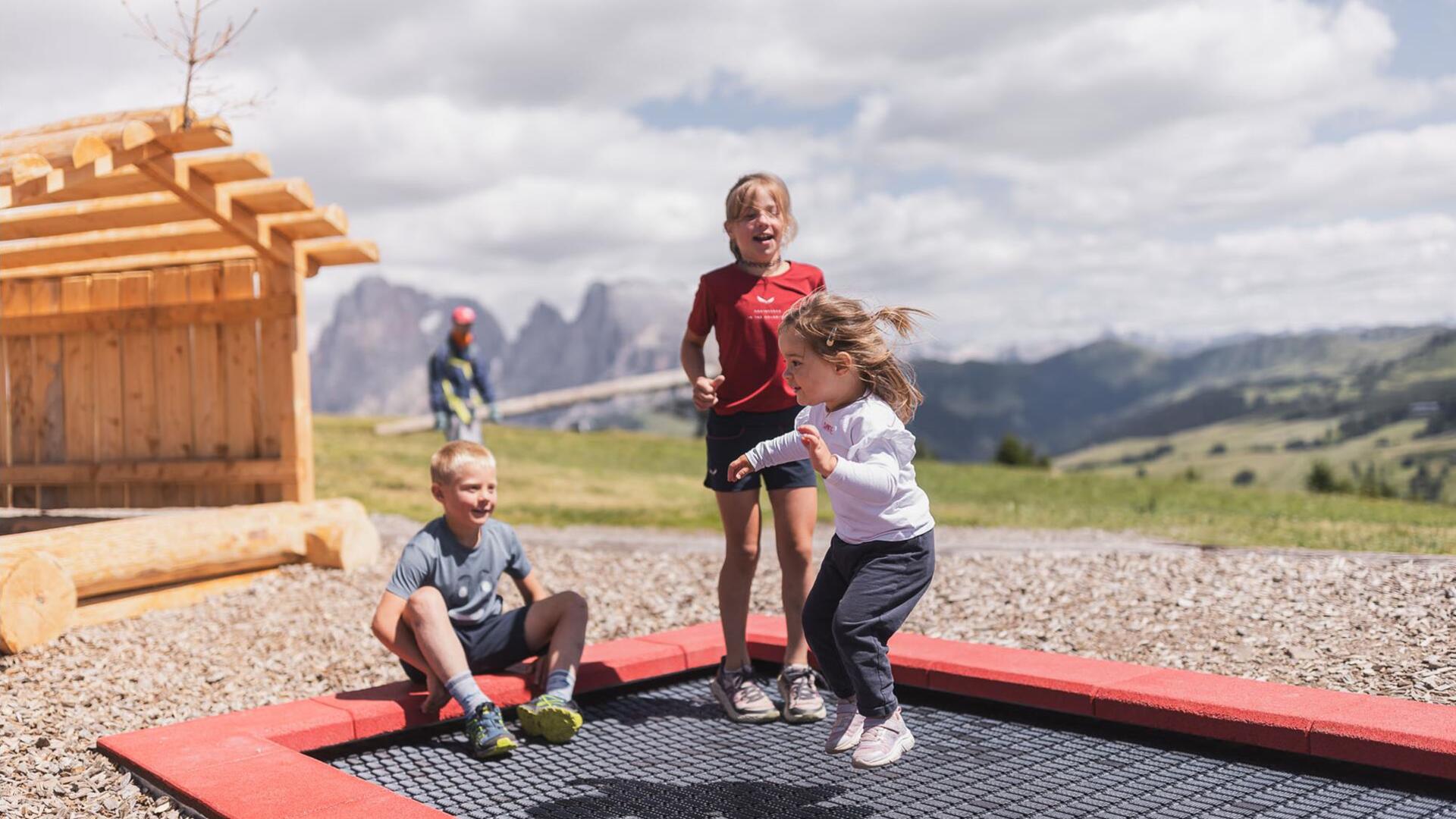 Three children are jumping on a trampoline