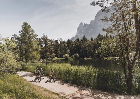 Three people are cycling around Lake Fiè
