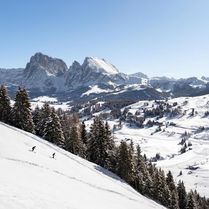 Ein Mann und eine Frau fahren eine Skipiste hinunter
