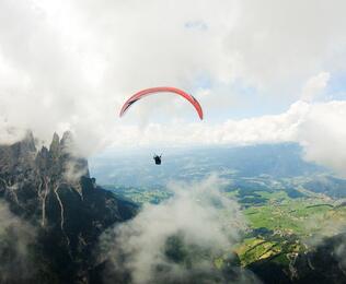 Eine Person beim Paragliden, im Hintergrund erhebt sich der Schlern