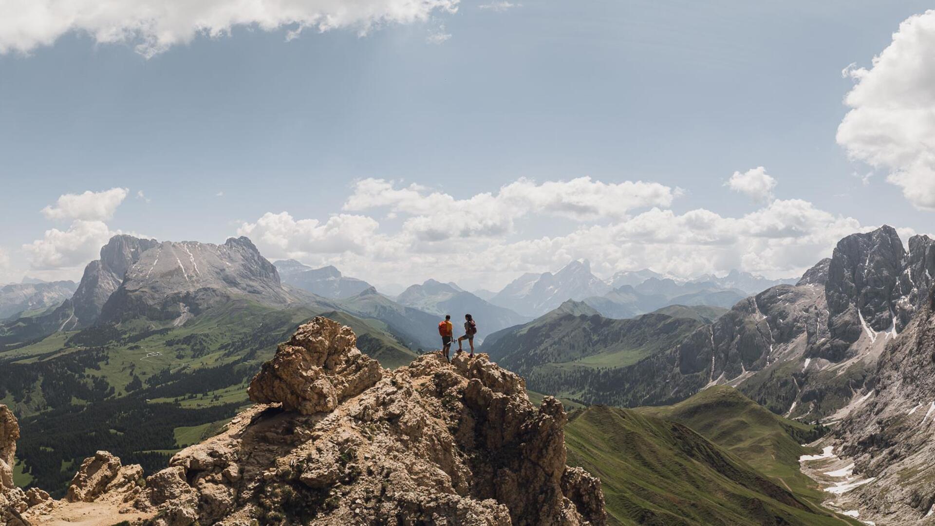 A man and a woman stand on a mountain summit