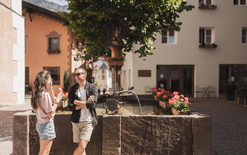 A man and a woman are standing next to a fountain