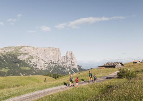 A family with two children hiking, with the Schlern in the background