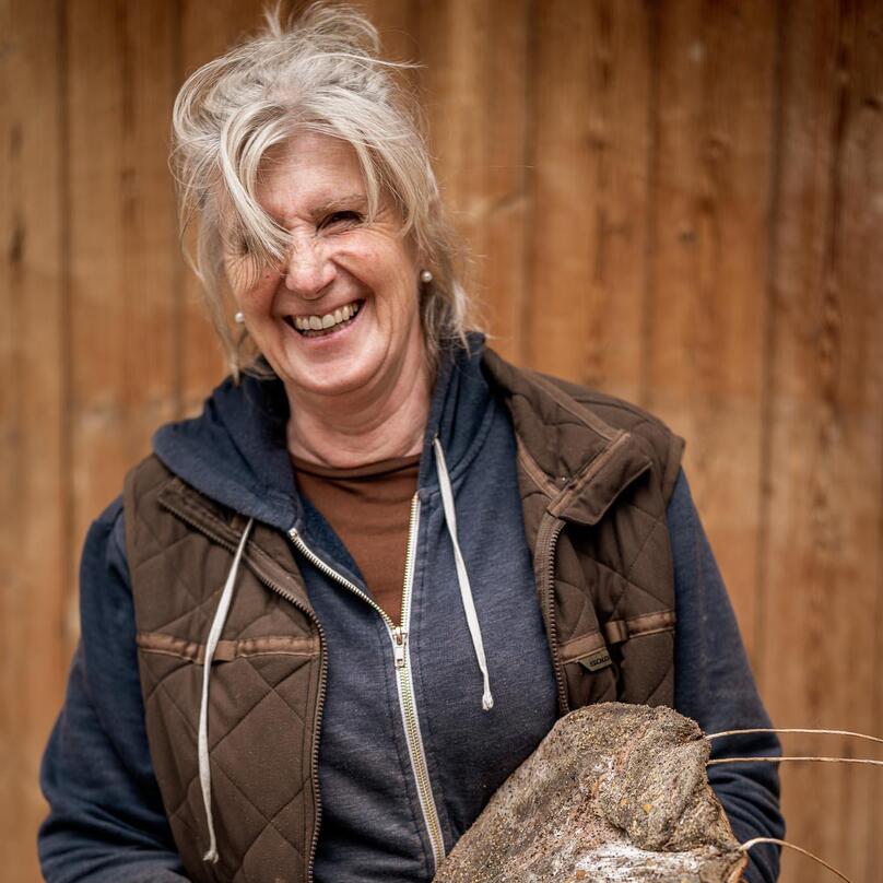 A woman is holding a piece of speck in her hand