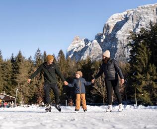 A family with one child is ice skating