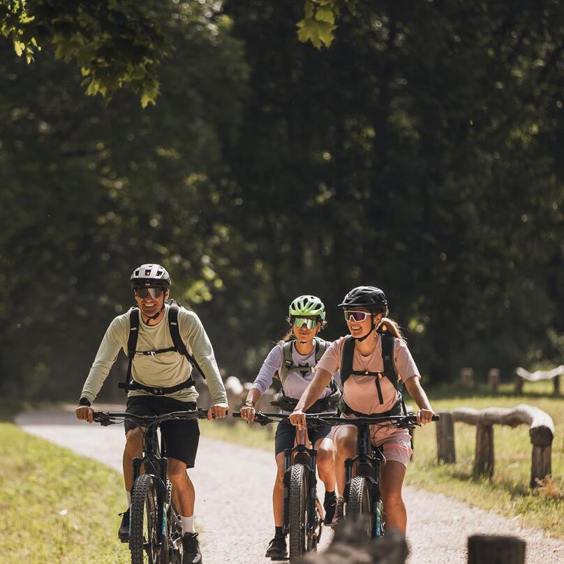 Three mountain bikers are riding along a bike path