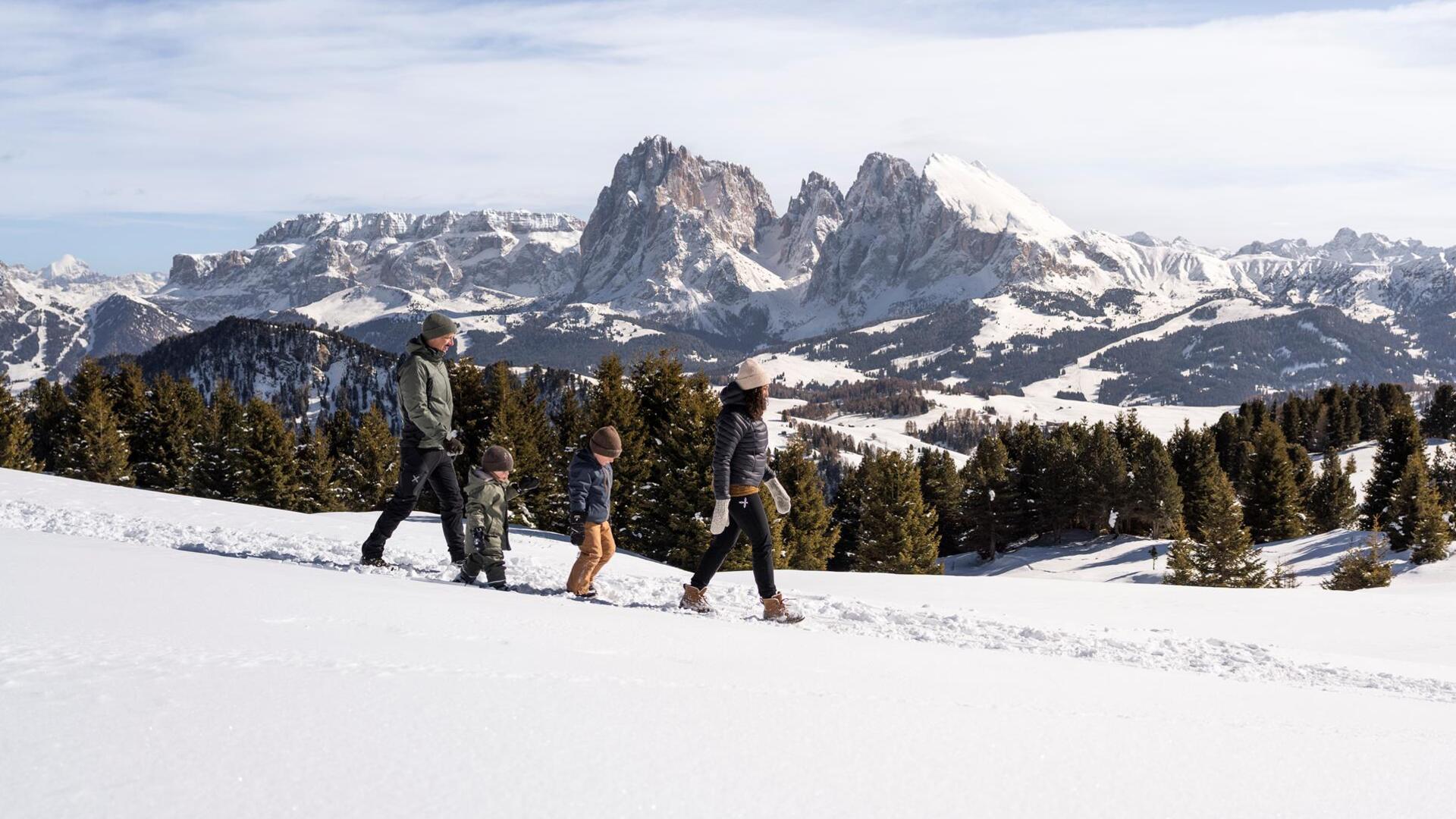 Eine Familie mit zwei Kindern stapft wandert im Schnee