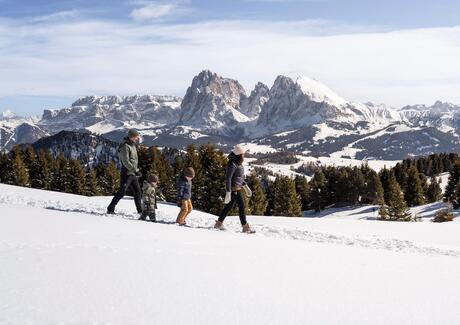 Eine Familie mit zwei Kindern stapft wandert im Schnee