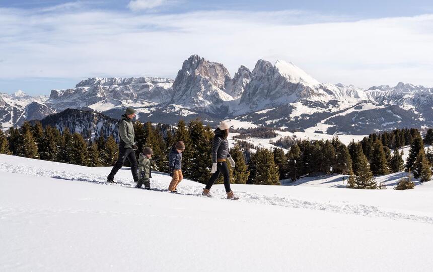 Eine Familie mit zwei Kindern stapft wandert im Schnee