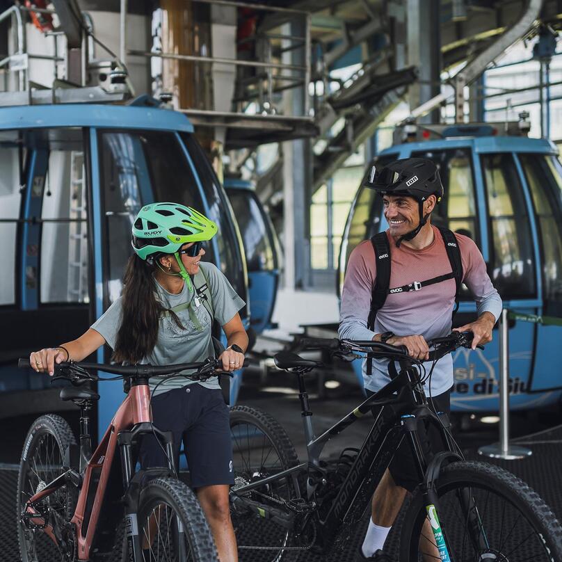 Ein Mann und eine Frau steigen mit ihren Fahrrädern aus der Umlaufbahn Seiser Alm
