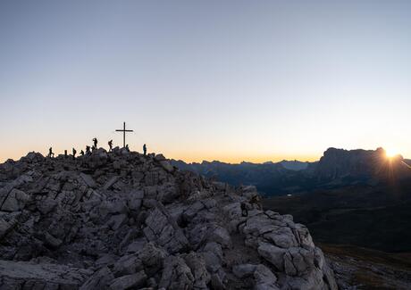 People stand on a mountain summit at sunrise