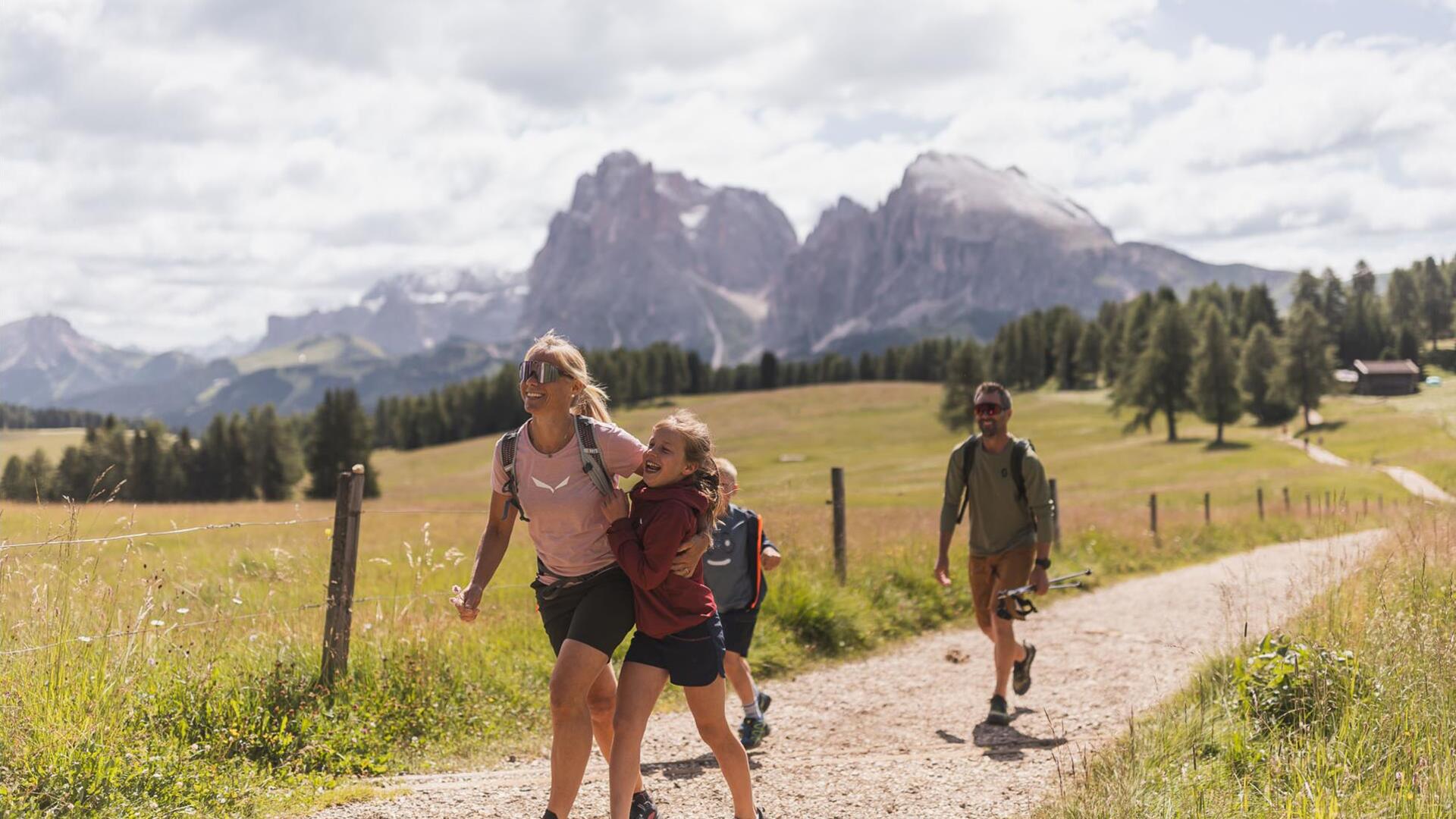 Eine Familie mit zwei Kindern wandert auf der Seiser Alm, im HIntergrund der Schlern