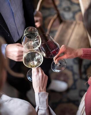 Drei Personen stoßen gemeinsam mit einem Glas Wein an