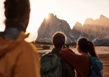 Zwei Männer und eine Frau blicken auf die Dolomiten im Abendlicht