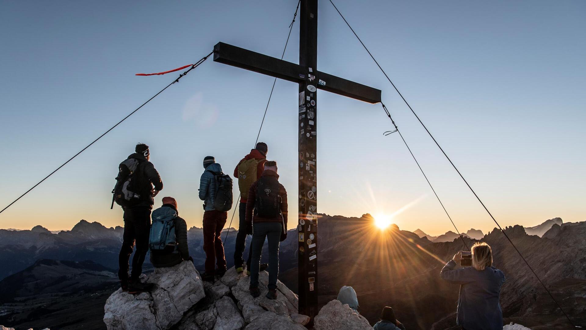 Eine Gruppe von Personen befindet sich auf einem Berggipfel bei Sonnenaufgang