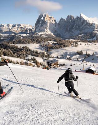 Ein Mann und eine Frau fahren eine Skipiste hinunter