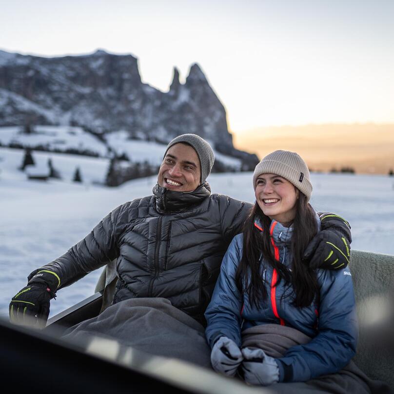A man and a woman are sitting in a horse-drawn carriage