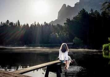 A woman is sitting on a jetty at Völser Weiher