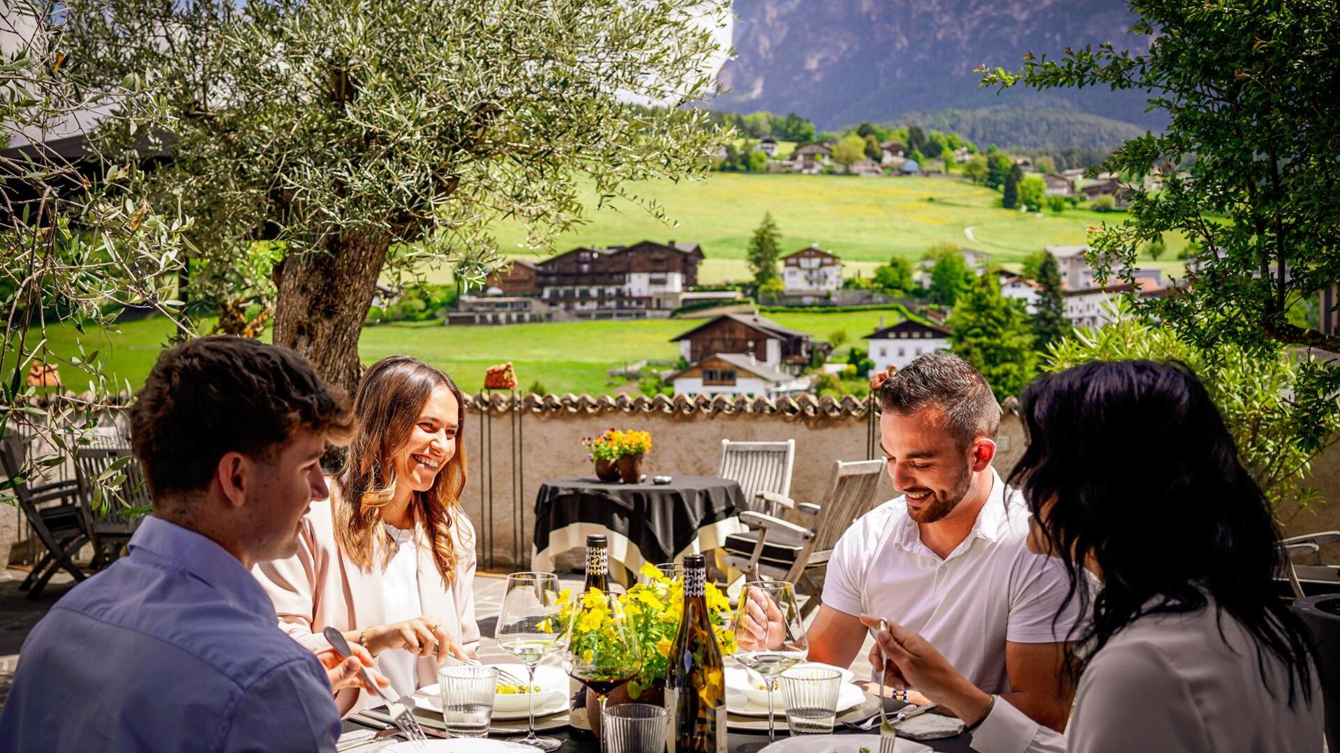 Zwei Männer und zwei Frauen sitzen an einem Tisch beim Essen