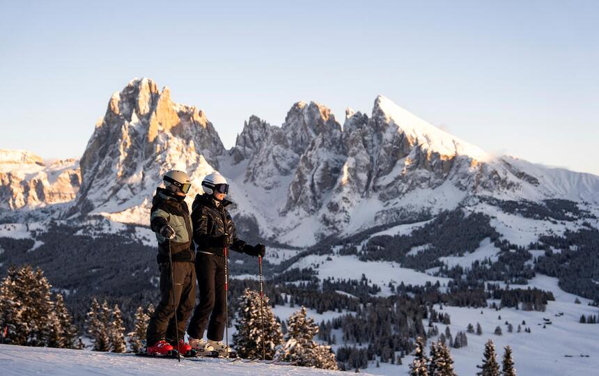 Ein Mann und eine Frau fahren eine Skipiste hinunter