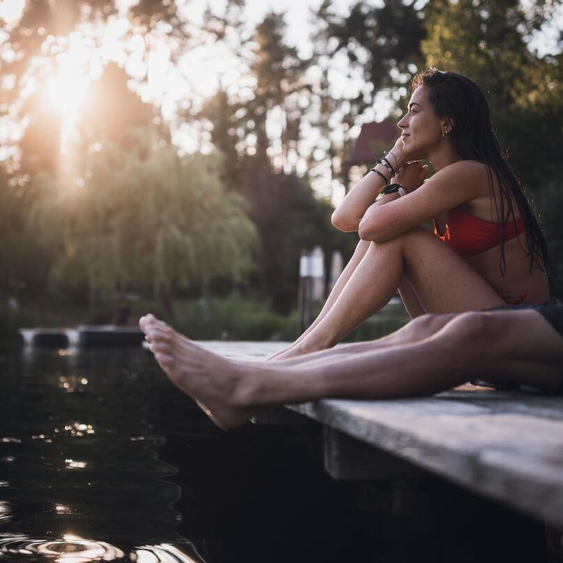 A man and a woman are sitting on a pier at Lake Fiè