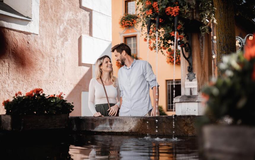 A man and a woman are standing in front of a fountain