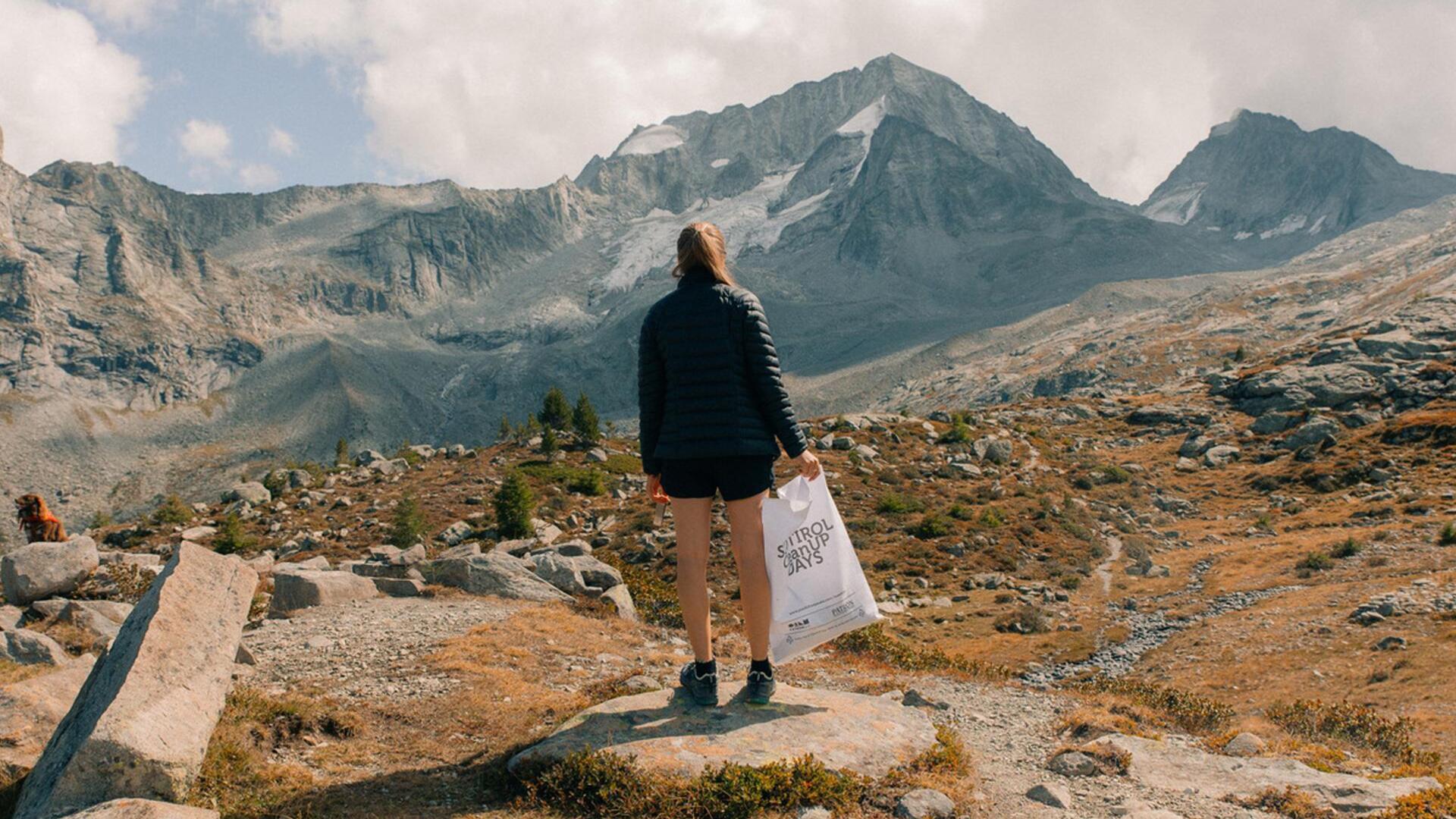 Una donna raccoglie rifiuti in montagna